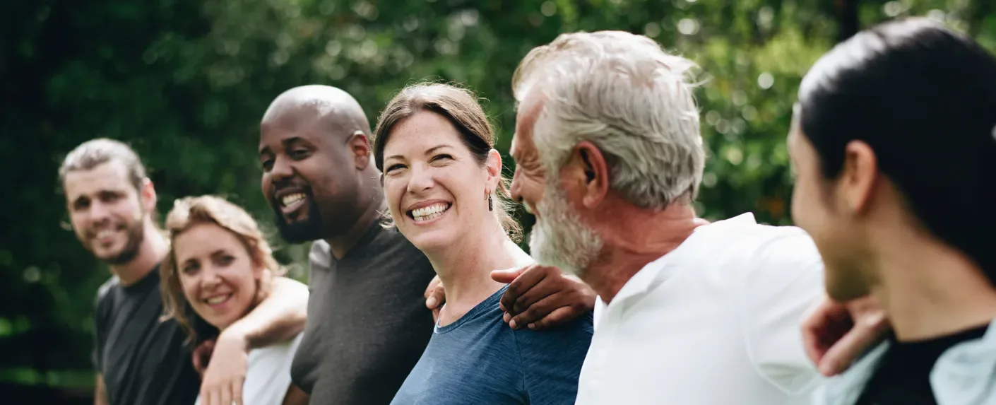 A group of adults standing together outdoors, smiling