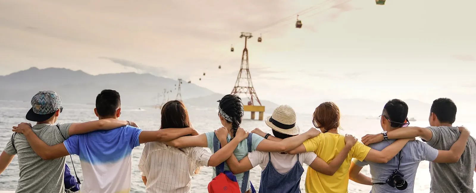 A group of friends standing arm in arm, looking out over the water